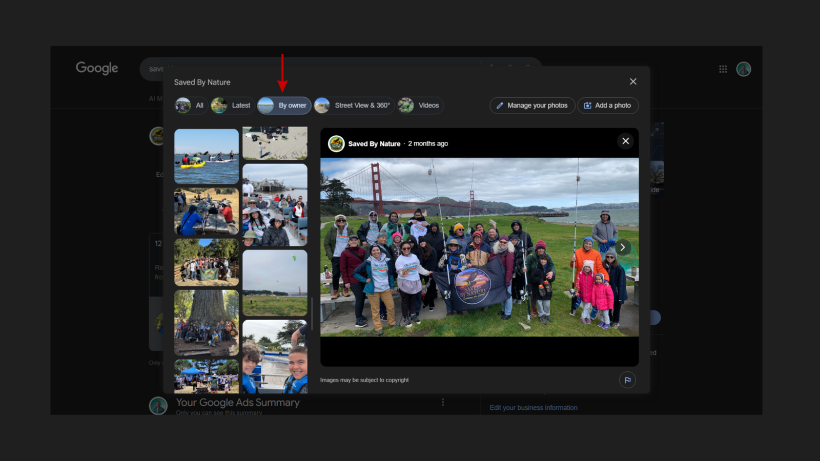 Google Business Profile photo library for Saved By Nature showing the By owner tab selected with a red arrow pointing to it, displaying a grid of owner-uploaded event photos including kayaking, coastal adventures, and group hikes, alongside an expanded view of a Bay Area Coastal Adventures group photo taken at the Golden Gate Bridge waterfront with the Saved By Nature flag visible, uploaded 2 months ago